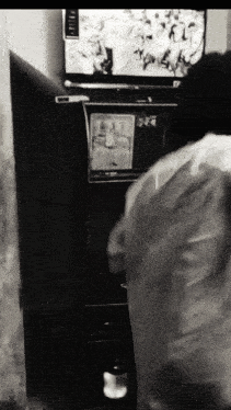 a black and white photo of a person in front of a tv