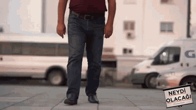 a man walking on a sidewalk with a sign that says neyd olacak