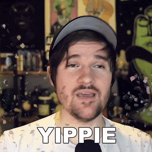 a man with a beard wearing a hat says yippie in front of a microphone