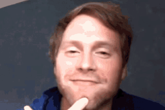 a close up of a man 's face with a finger on his chin