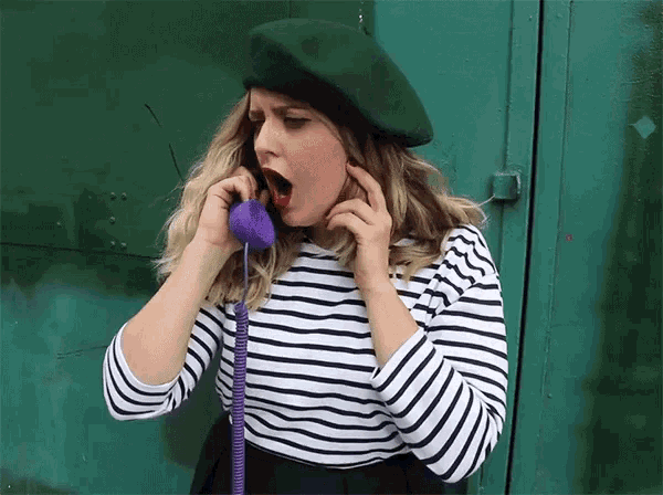 a woman wearing a green beret is talking on a phone
