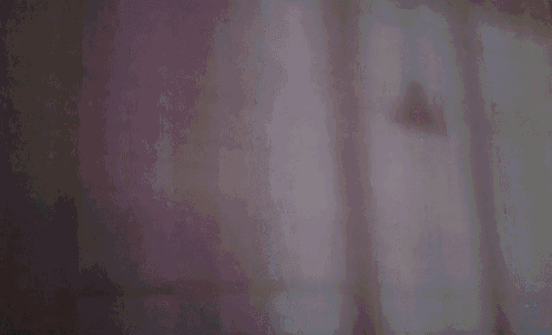 a dark room with a blue curtain hanging on the window .