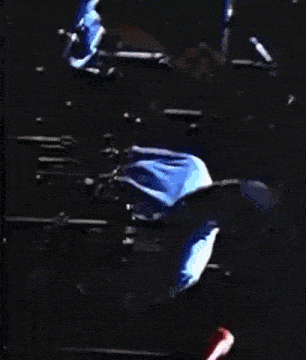 a man is playing drums on a stage in a dark room
