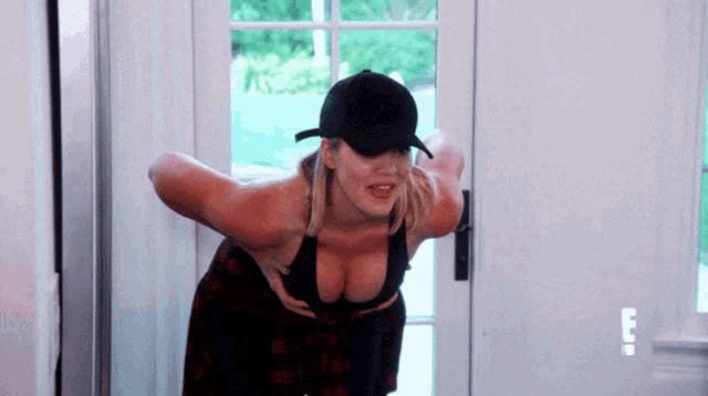 a woman wearing a baseball cap and a bra is standing in front of a white door