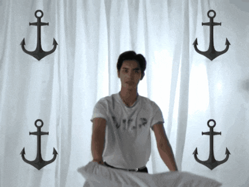 a man in a white shirt is standing in front of anchors on a white curtain