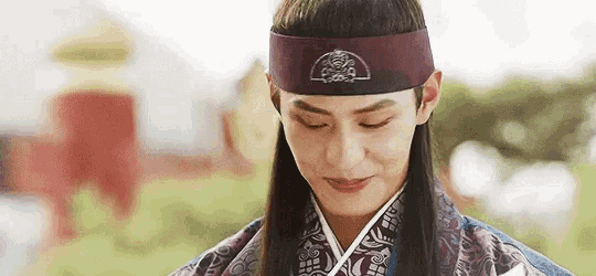 a man with long hair is wearing a headband and a traditional costume .