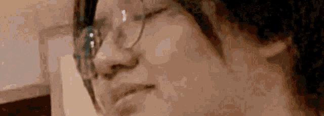 a close up of a person wearing glasses and making a funny face .