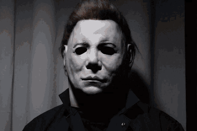 a man wearing a white mask with black eyes