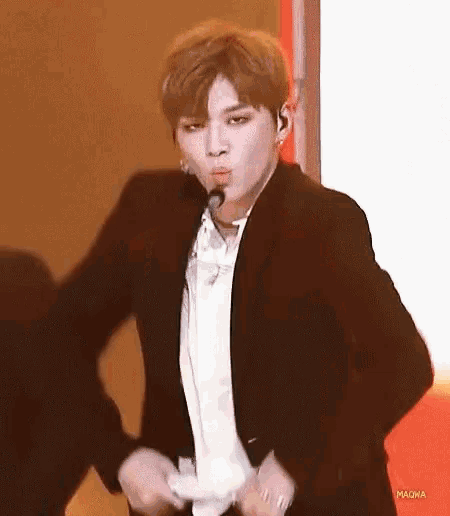 a man in a suit is dancing on a stage while wearing a microphone .