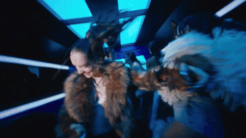 a woman in a fur coat is standing in a dark room with blue lights
