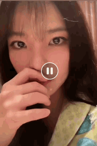 a close up of a woman 's face with a pause button in the corner