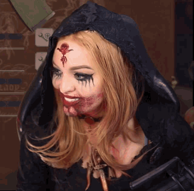 a woman with blood on her face is wearing a black hooded jacket