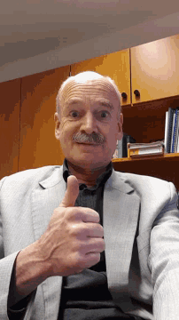 a man in a suit is giving a thumbs up sign