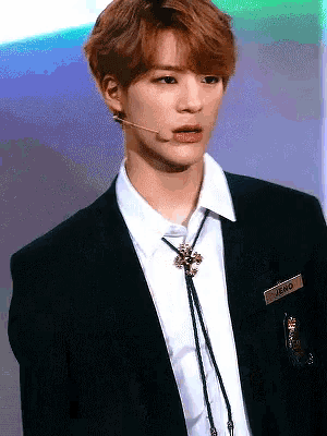 a young man wearing a black suit and a name tag that says jeno
