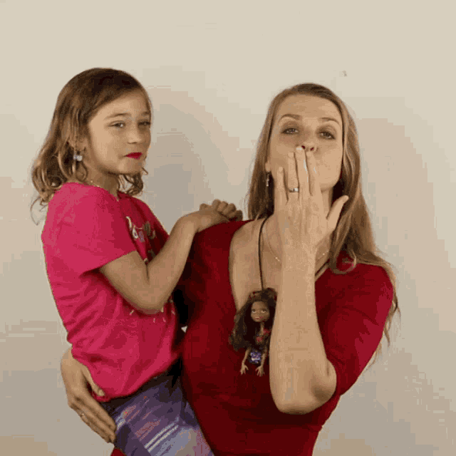 a woman in a red shirt is holding a little girl in her arms