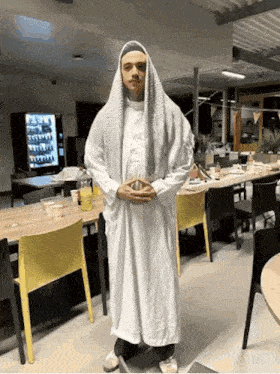 a man in a white robe stands in a room with a vending machine