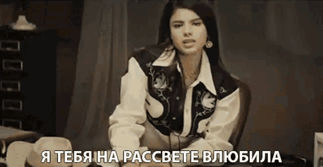 a woman in a cowboy jacket is sitting in a chair with a caption in russian that says " i love you "