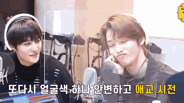 two young men are sitting in front of a microphone in a room .