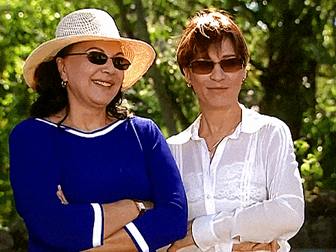 two women standing next to each other one wearing a hat and sunglasses