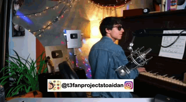 a man in a denim jacket is playing a piano with a microphone in front of him