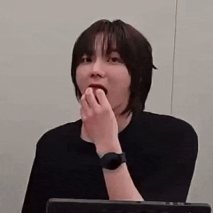 a woman with short hair is sitting in front of a laptop computer . she is wearing a watch on her wrist .