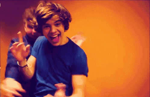 a man in a blue shirt is sticking his tongue out while another man holds his hand up