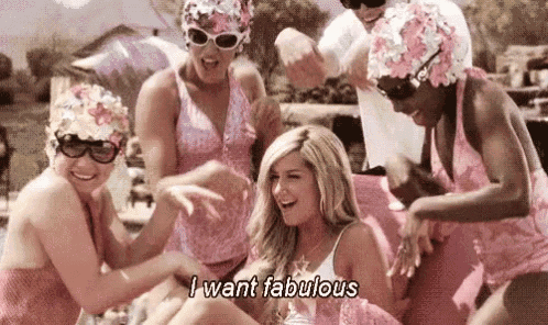 a group of women in pink swimsuits and swim caps are standing around a woman in a pink dress .