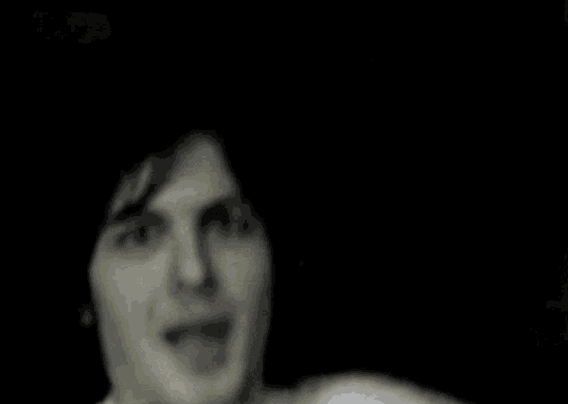 a man in a white shirt is smiling in a black background