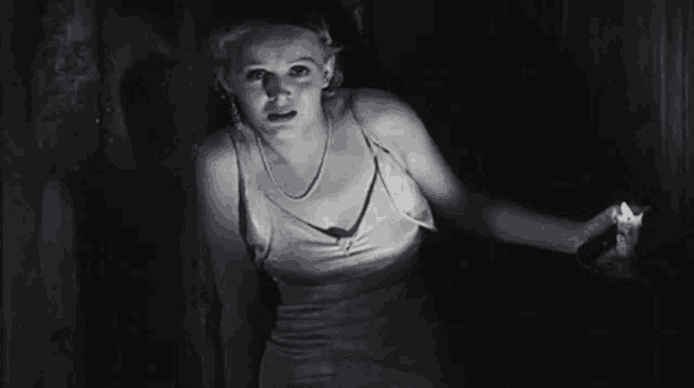 a black and white photo of a woman holding a candle in her hand .