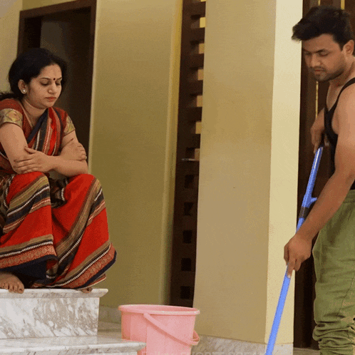 a woman sits on the steps while a man mops the floor