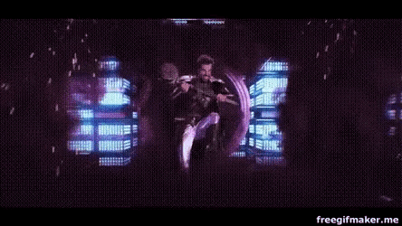 a man is dancing on a stage in front of a large screen with a purple background .