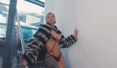 a woman in a fur coat and bikini is standing on stairs