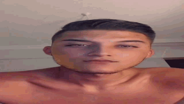 a young man without a shirt is taking a selfie with his face upside down .