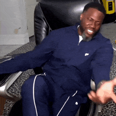 a man in a blue nike tracksuit is sitting in a chair