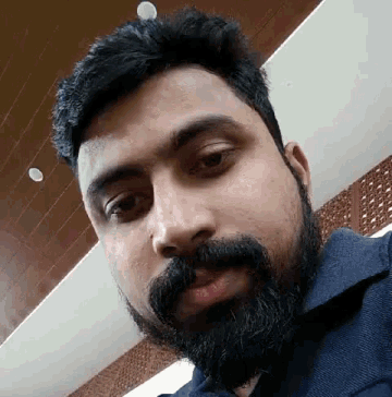 a man with a beard and mustache is taking a selfie in a room .