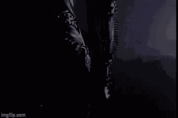 a close up of a person 's arm in a black leather jacket in a dark room .