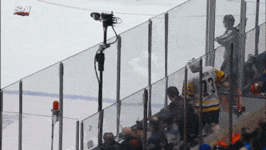 a hockey player with the number 13 on his jersey stands behind a glass fence