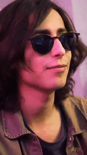 a young man with long hair wearing sunglasses and a brown jacket