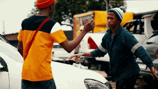 a man giving another man a high five while standing next to a car