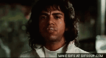 a man with long hair is making a funny face with his mouth covered in saliva .