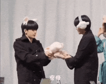 a man wearing bunny ears is holding a stuffed animal while another man holds a stuffed animal .
