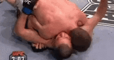 two men are wrestling in a ring and one of them is laying on the ground .