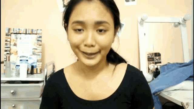 a woman in a black shirt is smiling in front of a mirror and a picture frame