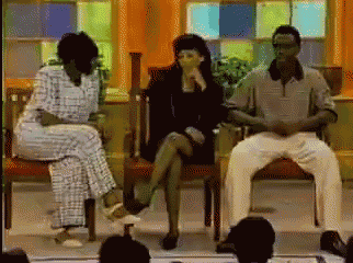 three people sit in chairs in front of a crowd