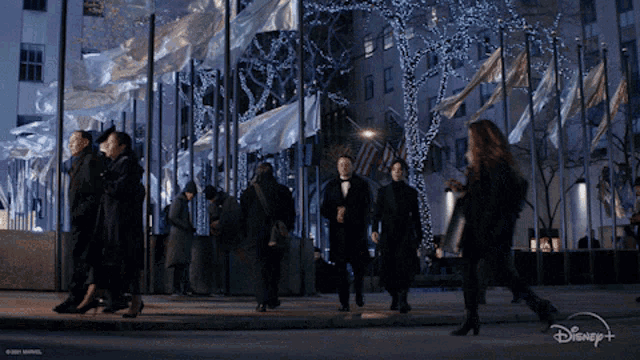 a group of people walking down a street with disney + written on the bottom right