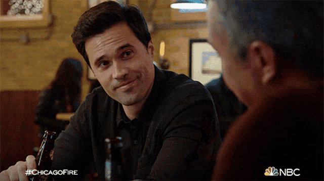 a man sitting at a table with a bottle of beer in his hand with the hashtag #chicagofire