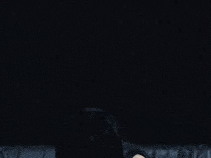 a woman in a black top and shorts is standing in front of a black couch