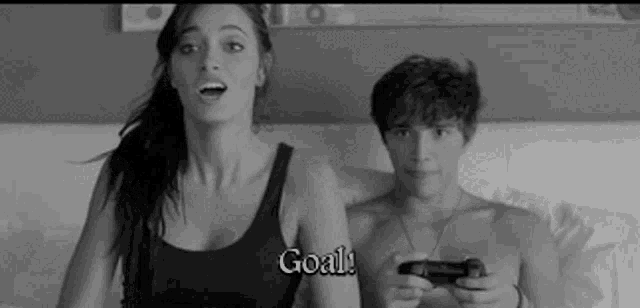 a man and a woman are playing a video game together and the woman is saying goal .