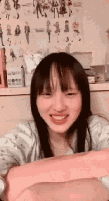 a girl with long black hair is smiling in front of a wall with drawings of girls on it