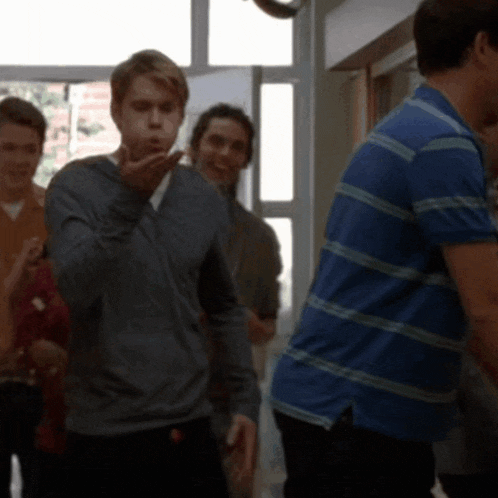 a man in a blue striped shirt blows a kiss to another man
